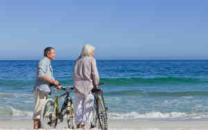 Elderly couple on beach with cycles
